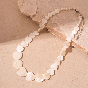 Macro shot of heart-shaped pearlescent beads on a shell-style necklace with silver clasp