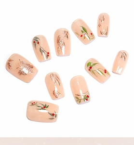 Detailed flat lay of press-on nails featuring golden butterflies and red cherry designs