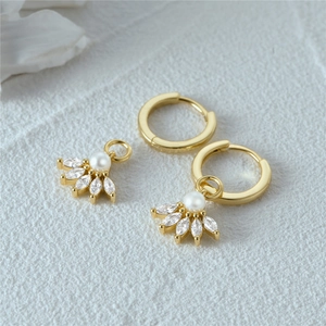 Detail of gold hoops with detachable pearl and marquise zircon charms on white fabric
