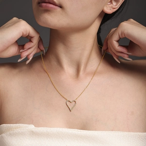 Elegant gold heart pendant necklace with micro-pave crystals on a female model