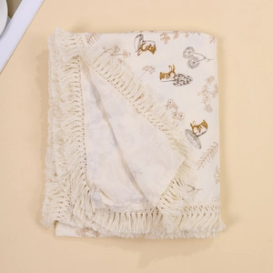 Detail of baby swaddle blanket with rabbit prints, floral patterns and tassel trim edges