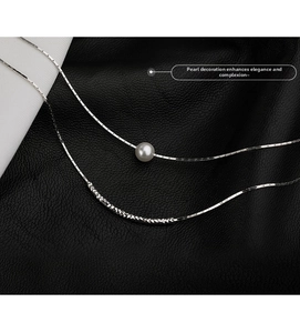 Detailed close-up of double-layer silver chain with white pearl and spiral texture