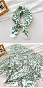 Detailed view of green and white geometric striped silk scarf showing texture and drape