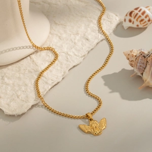 Vue détaillée d'un collier pendentif ange doré sur un décor de coquillage naturel