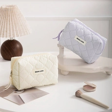 Detailed shot of quilted cosmetic bags in beige and lavender with BEER LOVE labels