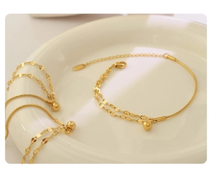 Detail of gold double-layered snake chain bracelet featuring a polished ball pendant