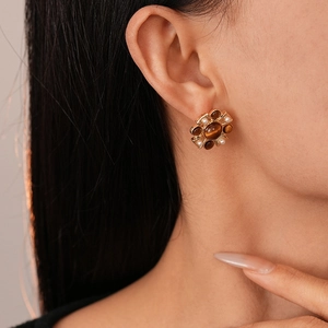Close-up of vintage flower stud earring with brown resin stone and white pearls on ear
