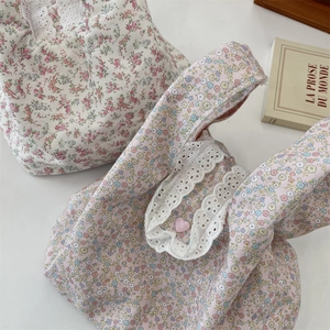Close-up of floral canvas wristlet bags with lace trim and heart button detail