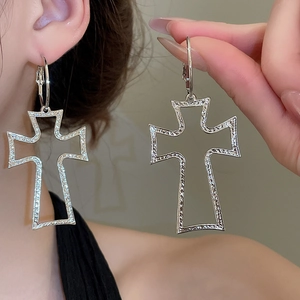 Close-up of silver hollow cross earrings with textured hammered finish on hoop
