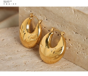 Detail of gold U-shaped hoop earrings with unique lava-like relief texture on stone