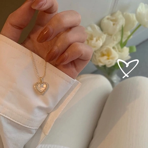 Detail of heart pendant necklace with shell inlay and crystals on a fine gold chain