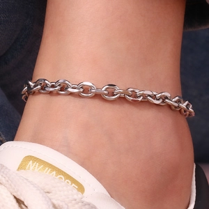 Detailed close-up of a minimalist silver stainless steel chain anklet worn on the ankle