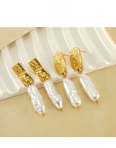 Detail of gold titanium steel earrings with baroque pearls and star embossed designs