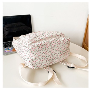 Detailed view of floral canvas backpack on a desk with laptop in a study setting