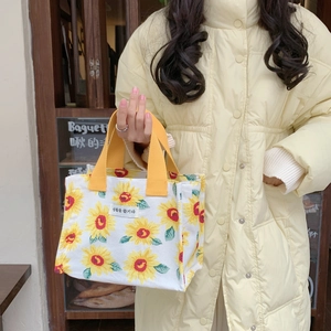 Detail of sunflower print canvas lunch bag with yellow handles and woven label