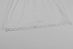Detailed view of the delicate lace hem on the elegant white off-shoulder mini dress