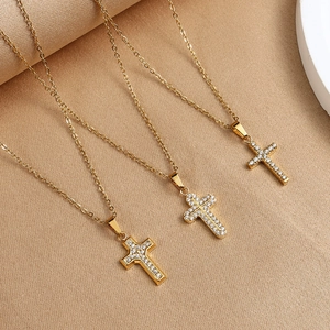 Detailed view of three gold cross pendants with pavé-set cubic zirconia on silk fabric
