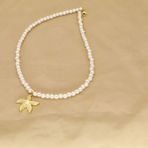 Detail of beaded necklace featuring white faux pearls and a golden starfish charm