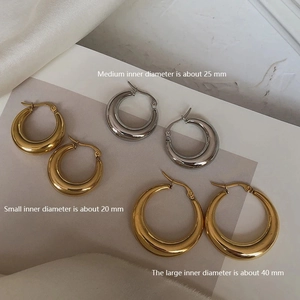 Polished gold and silver hoop earrings in 20mm, 25mm, and 40mm sizes on silk cloth