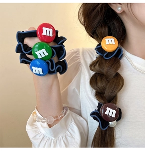 Détail de boutons en résine avec lettre M sur des chouchous en tissu plissé noir