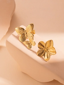 Macro detail of golden butterfly and flower rings on a minimalist beige base