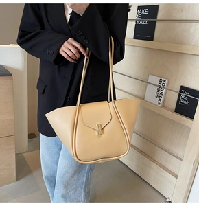 Dettaglio della borsa tote in pelle beige con una fibbia in metallo dorato lucido