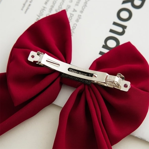 Elegant burgundy ribbon bow hair clip with silver spring metal fastener on magazine