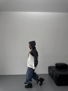 Side view of oversized hoodie with black and white color blocking and drawstring hood