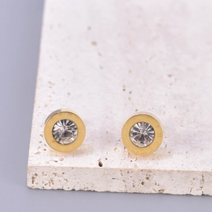 Détail de boucles d'oreilles dorées avec chiffres romains et un oxyde de zirconium central