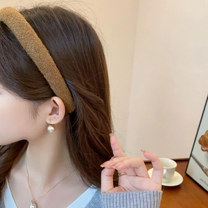Close-up of a brown fleece headband and elegant white pearl jewelry set on a model
