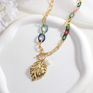 Bohemian gold leaf pendant necklace with colorful acrylic links and pearls on a white tray
