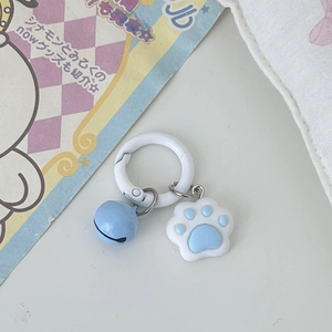 Detail of cute cat paw keychain with blue bell and white spring ring on pastel background