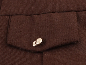 Detail of dark brown linen-cotton dress pocket with textured fabric and gold metal button