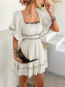 Close-up of square neck white dress with black trim and elegant ruffle details