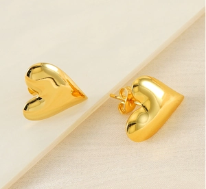 Close-up of heart-shaped gold studs featuring a highly polished mirror finish surface