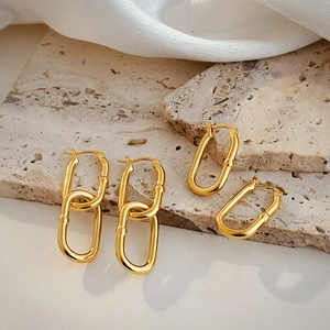 Detail view of 18K gold plated U-shaped chain earrings on silk fabric and stone