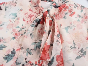 Detailed view of floral chiffon dress neckline with pink print and a chic bow tie