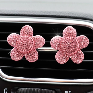Close-up of pink rhinestone flower car vent clips on a black interior air outlet
