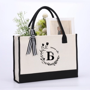 Close-up of canvas tote bag with black letter B, summer vibe print, and striped ribbon