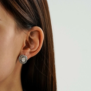 Detail of silver twisted earring with clear crystal stone on model's ear lobe