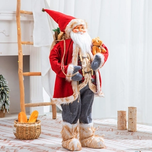 Standing Santa Claus doll holding a brown bear and gift bag in a festive home setting