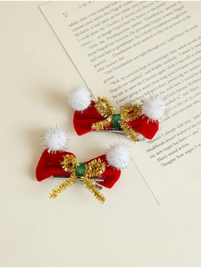 Détail de pinces à cheveux de Noël en velours rouge avec fil doré et boules en peluche