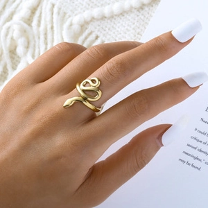 Close-up of a gold-plated snake wrap ring on a model hand with a minimalist book background