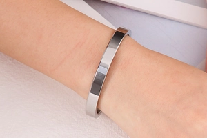 Close-up of polished silver stainless steel bangle bracelet on wrist for a minimalist style