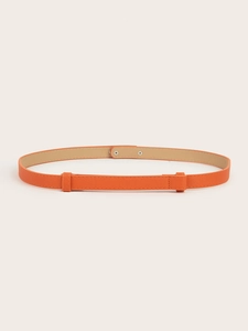 Close-up of orange cross-grain leather skinny belt with adjustable silver metal buckle