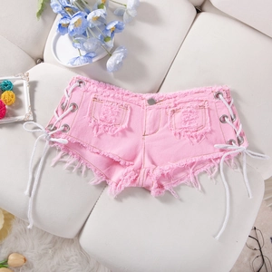 Dettaglio degli hot pants in denim rosa con lacci laterali e bordi sfrangiati sul divano
