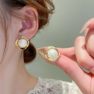 Detailed view of gold plated square twist earrings with elegant pearl inlay worn by model