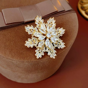 Macro view of gold-plated snowflake brooch with sparkling cubic zirconia on velvet box