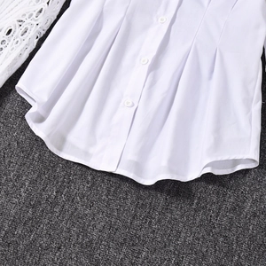 Detail of white long sleeve shirt showing button closure and hem pleat design details