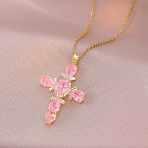Gold plated cross necklace with pink pear-shaped stones on elegant pink silk fabric